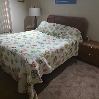Sale Photo Thumbnail #8: Mid-century modern style bedroom set including a wooden headboard and two matching two-drawer nightstands, shown with a seashell-patterned quilt.