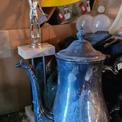 Sale Photo Thumbnail #25: Vintage silver-plated coffee or teapot with ornate feet and spout, showing heavy tarnish, displayed alongside a small athletic trophy.
