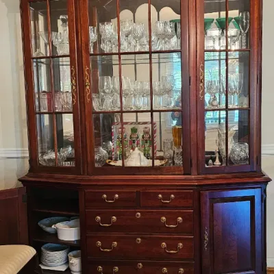 Sale Photo Thumbnail #11: Traditional mahogany china cabinet with an arched top, glass-front display shelves filled with crystal stemware, and a lower buffet base featuring drawers and cabinets.