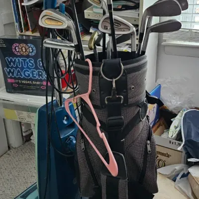 Sale Photo Thumbnail #20: Assorted golf clubs, including a Nike driver and various irons, housed in a grey and black patterned cart bag.