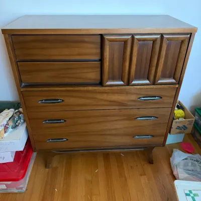 Sale Photo Thumbnail #37: Mid-century modern walnut gentleman's chest by United Furniture Corporation, featuring sculpted wood cabinet doors, recessed drawer pulls, and tapered legs.