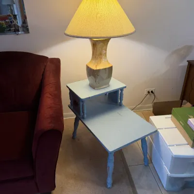 Sale Photo Thumbnail #12: Vintage two-tier step end table painted light blue, paired with a mid-century ceramic table lamp featuring a pleated shade.