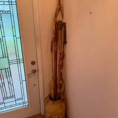 Sale Photo Thumbnail #18: Collection of rustic hand-carved wooden walking sticks and canes, displayed in a vintage painted metal milk can.