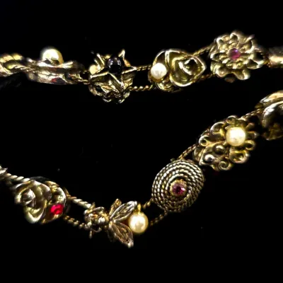 Sale Photo Thumbnail #64: Vintage gold-tone charm link bracelet featuring faux pearls, rhinestones, and floral motifs.
