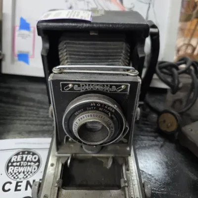 Sale Photo Thumbnail #47: Vintage Busch Pressman folding camera featuring a Graflex Photorecord lens and Betax No. 2 shutter, showing some wear consistent with age.