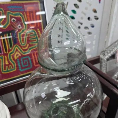 Sale Photo Thumbnail #104: Large hand-blown clear glass apothecary jar with a teardrop-shaped lid, featuring natural air bubbles and a green-tinted base.