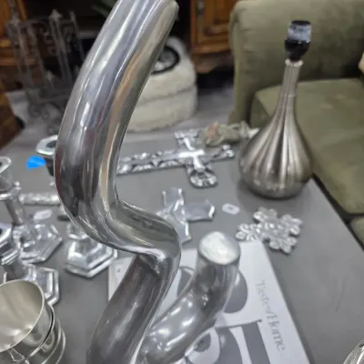 Sale Photo Thumbnail #25: Modernist polished aluminum or pewter sculptural vase with a wavy, organic form, displayed alongside other silver-toned decorative items.
