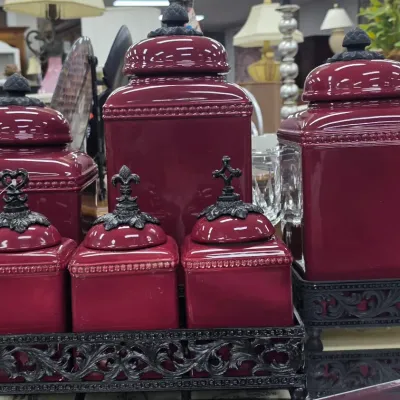 Sale Photo Thumbnail #7: Six-piece burgundy ceramic canister set featuring beaded trim, black metal finials, and matching scrollwork metal bases.