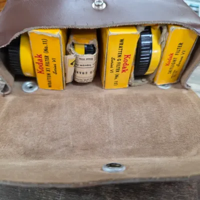 Sale Photo Thumbnail #37: Vintage Kodak Series VI camera filters in their original yellow boxes, stored inside a brown leather snap-closure pouch.