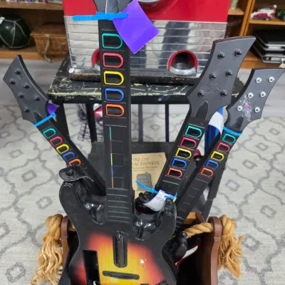 Sale Photo Thumbnail #46: Collection of four vintage Guitar Hero controller guitars, including a sunburst model, stored in a wooden bin.