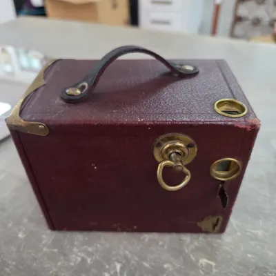 Sale Photo Thumbnail #43: Antique Kodak No. 2 Bulls-Eye box camera in maroon leatherette with brass hardware and a leather carrying handle, circa early 1900s.