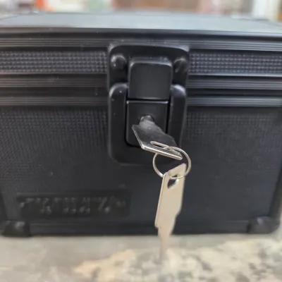 Sale Photo Thumbnail #40: Small black aluminum lockbox with a textured finish, featuring a front latch with two keys inserted in the lock.