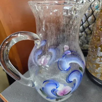 Sale Photo Thumbnail #24: Hand-painted clear glass pitcher featuring blue and pink floral motifs with a textured, bubbly glass finish.