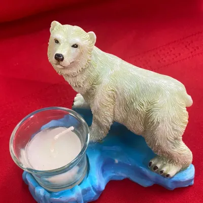 Sale Photo Thumbnail #55: Polar bear figurine candle holder, featuring a resin polar bear on a blue ice-like base with a small glass votive cup.