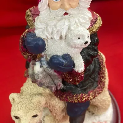 Sale Photo Thumbnail #56: Hand-painted resin Santa figurine riding a polar bear, holding a white bear cub and fish, mounted on a wooden base.