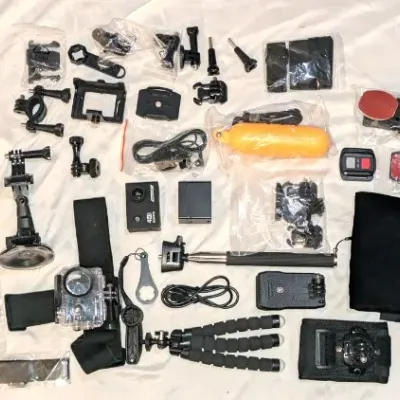 Sale Photo Thumbnail #3: Assorted action camera accessories and mounts, including a mini tripod, suction cup mount, floating handle, straps, and various hardware pieces.