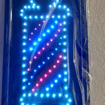Sale Photo Thumbnail #20: Modern LED barber pole sign, illuminated in blue and red lights, still in its original protective plastic wrap.