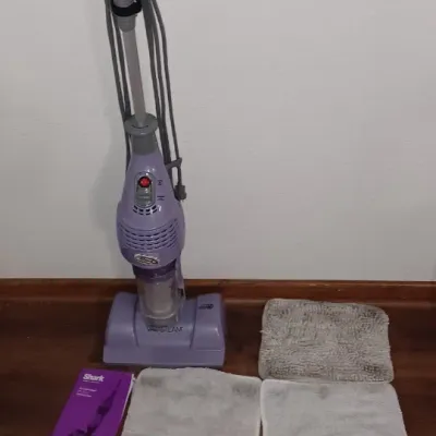 Sale Photo Thumbnail #27: Shark purple steam mop with three microfiber pads, user manuals, and additional cleaning attachments.