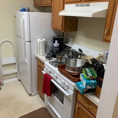 Sale Photo Thumbnail #15: Frigidaire white top-freezer refrigerator and matching gas range, surrounded by oak kitchen cabinetry and various small kitchen appliances and cookware.
