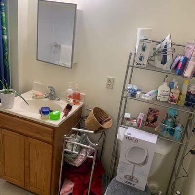 Sale Photo Thumbnail #18: Bathroom vanity with sink, medicine cabinet, and metal shelving unit holding various toiletries, a Conair fabric steamer, and a boxed Conair Halo makeup mirror.