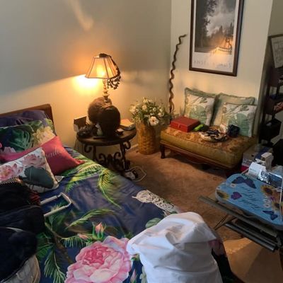 Sale Photo Thumbnail #22: Bedroom furniture and decor, including a floral-patterned bedspread, a wrought-iron side table with a lamp, a small upholstered bench, and a framed Ansel Adams poster.