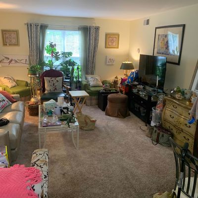 Sale Photo Thumbnail #21: Eclectic living room featuring a variety of furniture, including a leather sofa, green armchairs, a glass-top coffee table, and a vintage-style painted chest of drawers.