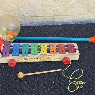 Vintage Fisher-Price Pull-A-Tune xylophone with mallet and a classic Corn Popper push toy, showing signs of play wear.