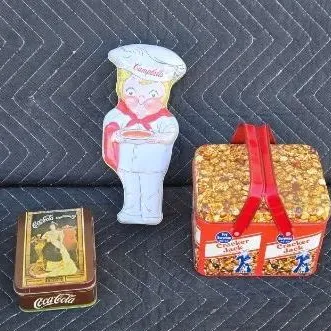 Vintage advertising collectibles including a Campbell's Soup chef plush doll, a small Coca-Cola tin, and a Cracker Jack tin designed...