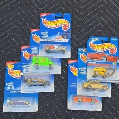 Collection of seven vintage Hot Wheels die-cast toy cars in their original blister packaging, dating from the late 1990s.