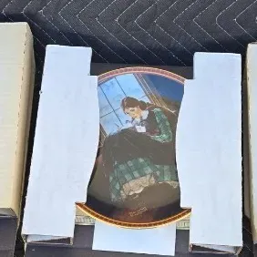 Three Norman Rockwell collector plates in their original cardboard packaging, featuring classic illustrated scenes.