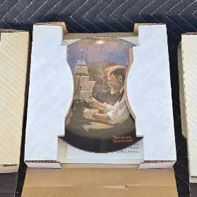 Three Norman Rockwell collector plates in their original cardboard packaging, featuring classic illustrated scenes.