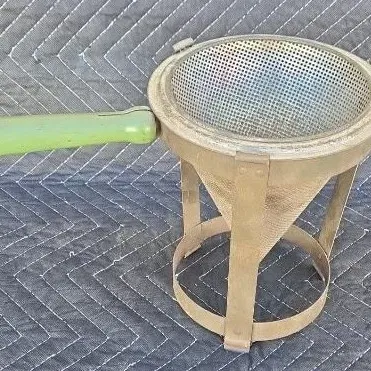 Vintage Foley food mill with a green wooden handle, complete with its original metal stand.