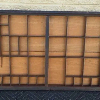 Vintage wooden printer's type tray with various sized compartments, showing some wear and age.