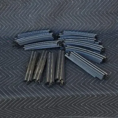 Assortment of HO scale model train track pieces, including curved and straight sections with integrated black roadbed.