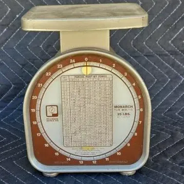 Vintage Pelouze Monarch postal scale with a 25-pound capacity, featuring a detailed parcel post zone chart on the face.