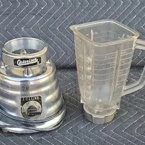 Vintage Osterizer Deluxe beehive blender with a chrome base and a clear plastic measuring pitcher.