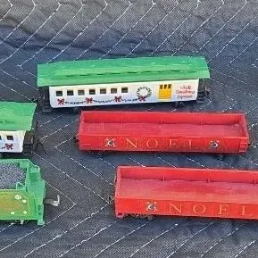Assorted vintage plastic Christmas-themed toy train cars, including "Merry Christmas" boxcars, "Noel" gondolas, and...
