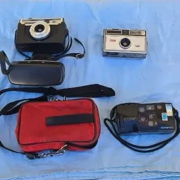 Collection of vintage cameras, including an Olympus point-and-shoot, a Kodak Instamatic, and a classic rangefinder style camera with a...