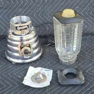 Vintage Osterizer Deluxe beehive blender with chrome base, glass jar, lid, and replacement blade assembly.