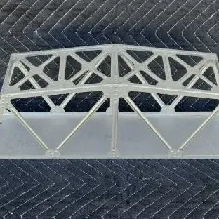 Vintage silver-painted metal truss bridge accessory for model train layouts, showing some light wear.