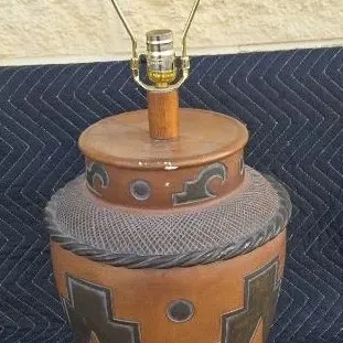 Southwestern-style ceramic table lamp featuring geometric patterns in brown and black tones, complete with a brass harp and wooden finial.