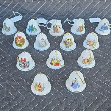 Collection of thirteen vintage Disney porcelain bell ornaments, featuring various classic characters in festive holiday scenes.