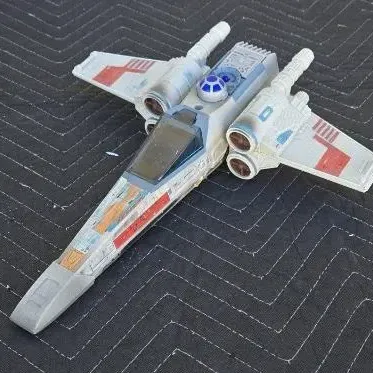 Vintage Kenner Star Wars X-Wing Fighter toy, showing some play wear and missing the front canopy glass and laser cannons.