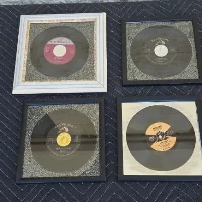 Four framed vintage 45 RPM vinyl records, including releases from RCA Victor and Specialty Records, presented in square frames with...