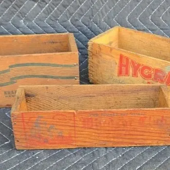 Three vintage wooden cheese boxes, including Kraft American, Hygrade, and a smaller box with red graphics, showing age-appropriate wear...