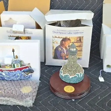 Collection of Cheryl Spencer Collin Lighthouses collectible figurines, including a lighthouse on a wooden base and a boat figurine,...