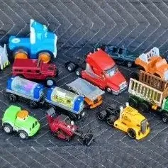 Assorted collection of children's toy vehicles, including trucks, cars, and construction equipment in various colors and styles.
