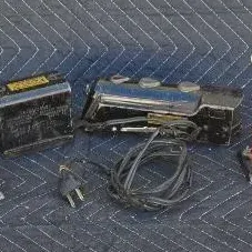 Vintage Lionel toy train accessories, including a railroad crossing sign, a lamppost, and a transformer, showing signs of age and wear.