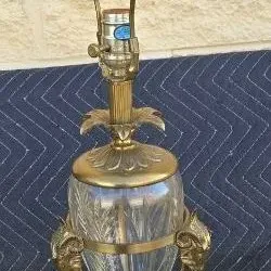 Vintage Hollywood Regency style brass and cut glass table lamp featuring ram's head accents and a faceted crystal finial.