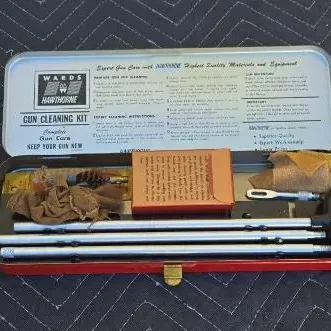 Vintage Wards Hawthorne gun cleaning kit in its original red metal tin, complete with cleaning rods, patches, and instructions.